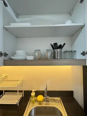 a kitchen with a sink and a shelf with dishes at MOA Staycation at Shore Residences Tower C in Manila