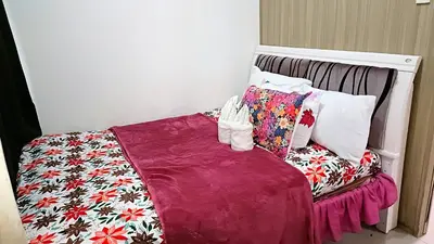 a bed with colorful pillows on top of it at Pool view from one-bedroom condo at Shore Residence in Manila