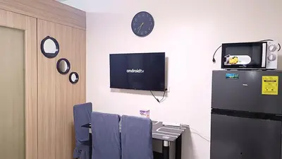 a room with a tv and a table with chairs at Pool view from one-bedroom condo at Shore Residence in Manila