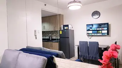 a living room with a refrigerator and a kitchen at Pool view from one-bedroom condo at Shore Residence in Manila