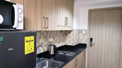 a kitchen with a sink and a black refrigerator at Pool view from one-bedroom condo at Shore Residence in Manila