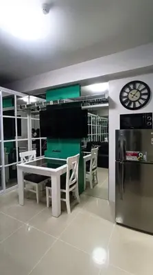 a dining room with a table and a clock on the wall at One-bedroom condo at Shell Residences in Manila