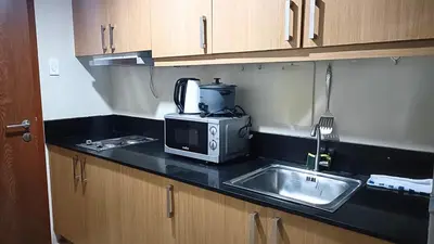 a kitchen counter with a microwave and a sink at Spacious simple one-bedroom condo at Shell Residence in Manila