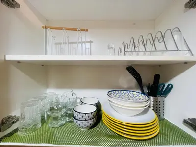 a kitchen counter with plates and bowls on a shelf at Luna Suite in Manila