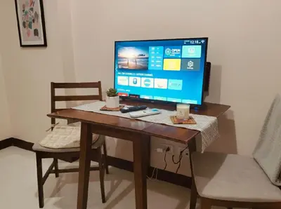 a computer monitor on a wooden table with two chairs at Cheap Accommodation - Newport Boulevard in Manila