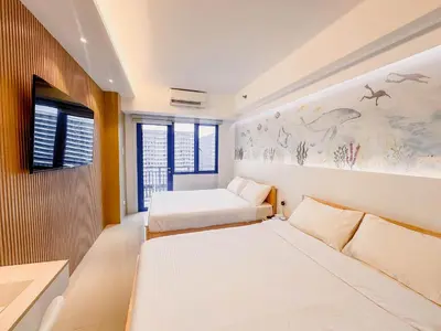 a bedroom with two beds and a tv on a wall at Hotel-Like Staycation 4 near MOA with WiFi & Netflix in Manila