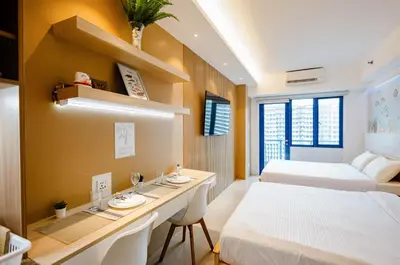 a hotel room with two beds and a desk in it at Hotel-Like Staycation 4 near MOA with WiFi & Netflix in Manila
