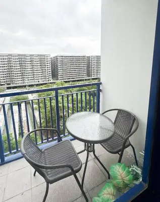 a table and chairs on a balcony with a view of a city at Hotel-Like Staycation 4 near MOA with WiFi & Netflix in Manila