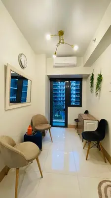 a living room with chairs and a clock on the wall at Luna Suite in Manila