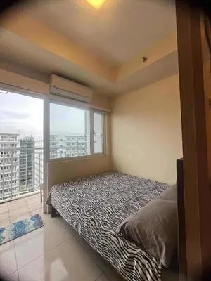 a bedroom with a bed and a large window at Dona staycation in Manila