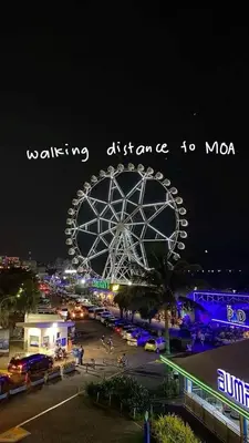 a large ferris wheel at night with the words walking distance tomo at SkyShore Suites in Manila