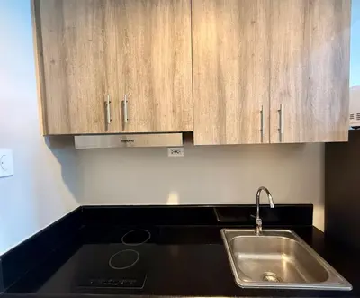 a kitchen with a sink and wooden cabinets at Coast Residences 40th Floor Penthouse Pasay Manila in Sampong
