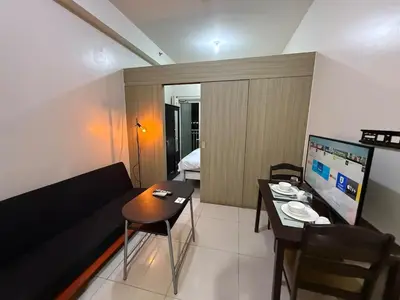 a living room with a couch and a table with a television at Pocco-breeze- inhouse pool in Manila