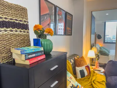 a dresser with books and a vase with flowers on it at Unique and Quiet Studio Unit in Mandaluyong or Makati with Fast WiFi & Best City View in Manila