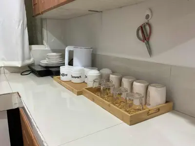 a kitchen counter with a shelf with cups and dishes at DBK HOMES Sorrento Oasis in Manila