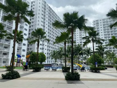 a large building with palm trees in front of it at Near MOA - Cozy Staycation 22D in Manila