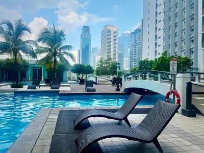 a swimming pool with chairs and a bridge in a city at Your Urban Oasis in the Heart of Makati in Manila