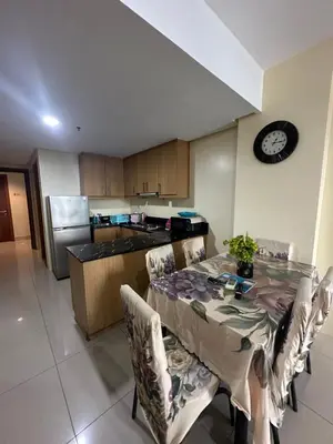 a kitchen with a table with chairs and a clock on the wall at Shell Residences -weng's-place in Manila