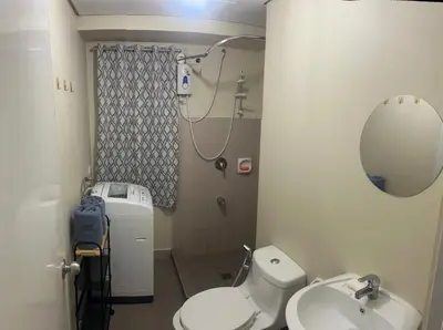 a bathroom with a toilet and a sink and a mirror at New 1BR in Mandaluyong 40SQM in Manila