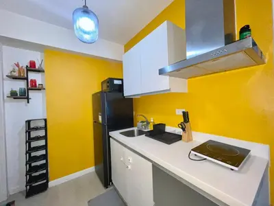 a kitchen with yellow walls and a black refrigerator at Azure Urban Resort Residences Parañaque City in Manila
