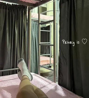 a person laying on a bed looking at a window at Roomies Spacious Fully Furnished Condo with Balcony and Netflix for 4pax in Manila