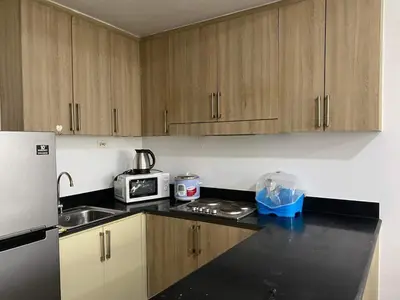 a kitchen with wooden cabinets and a white refrigerator at Shore Residence 2br 5f walking distance MOA near airport in Manila