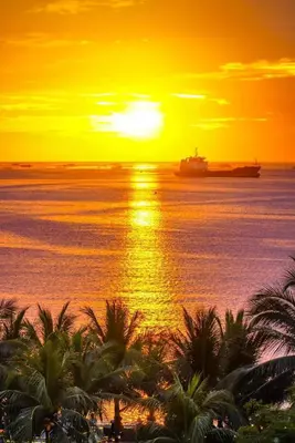 a sunset over the ocean with a container ship at Shore Residence 2br 5f walking distance MOA near airport in Manila
