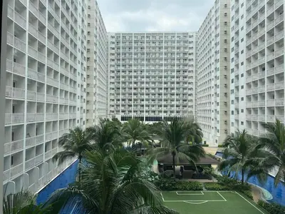 a view of a large building with palm trees and a tennis court at SHORE Residence d42 walking distance MOA near Airport in Manila