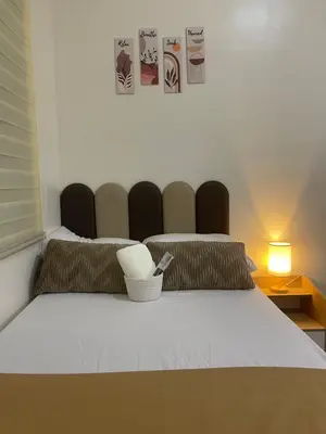 a bedroom with a bed with two chairs at Sky Condotel Staycation in Manila