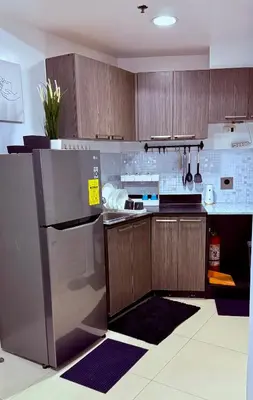a kitchen with wooden cabinets and a stainless steel refrigerator at Vista Shaw Residences in Manila