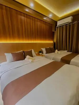 two beds in a room with wooden walls at Cozy Escape Shore 2 Tower 3 -MOA - Pasay- 2 Beds in Manila