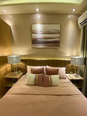 a bedroom with a bed with two lamps on either side at Hallin Bay Suites Modern 1BR with balcony in Manila