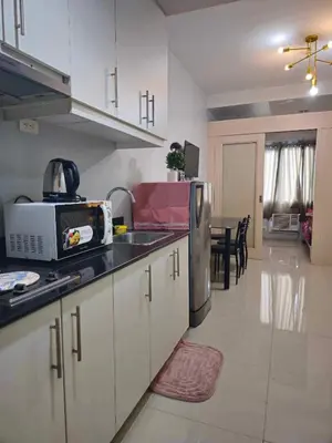 a kitchen with a sink and a refrigerator and a table at Sea Residences SM Mall of Asia Cj in Manila