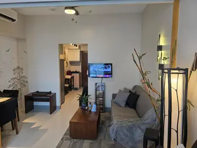 a living room with a couch and a tv at Very Cosy One Uptown near Grand Hyatt Hotel BGC Uptown Mall and St Lukes Medical Center in Manila