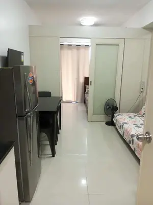 a room with a refrigerator and a table and a bed at Tower F Sea Residence in Manila