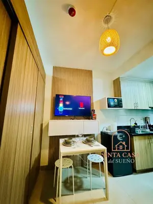 a kitchen with a small table with two stools and a television at Sinta Casa del Sueno MOA Stay with Pool and Wi-fi in Manila