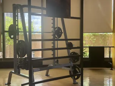 a gym with a squat rack in a room with windows at Levi & Moon's Manila Bay in Manila