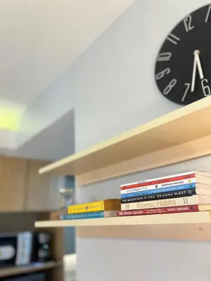 a stack of books on a shelf with a clock at Condo Living at Shore with Parking in Manila