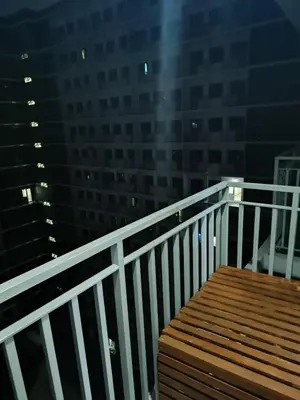 a wooden bench sitting on a balcony at night at SkyShore Suites in Manila