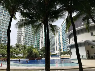 a swimming pool with palm trees in front of buildings at Azure Urban Resort Residences - St Tropez Tower in Manila