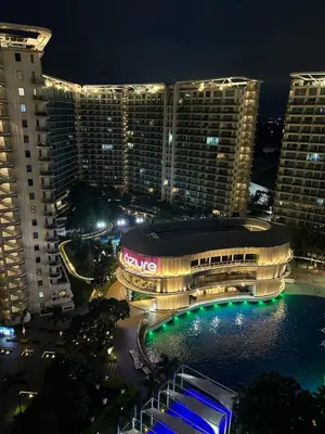 a large building with lights in front of buildings at night at Azure Urban Resort Residences - St Tropez Tower in Manila