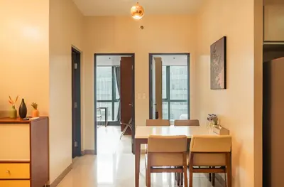 a dining room with a table and chairs at One Uptown 2 Bedroom with 3 Beds Uptown Mall View in Manila