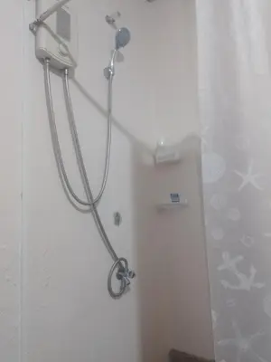 a shower with a hose attached to a wall at Sunvalley B&b in Manila