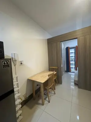 a kitchen with a wooden table and a refrigerator at FAME RESIDENCES CONDO-TEL Near EDSA Shang in Manila