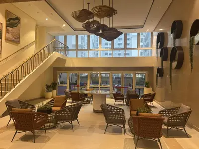 a lobby with chairs and tables and a staircase at JUANderful Home at Park McKinley West in Manila