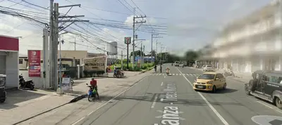 a yellow car is driving down a city street at Auntie's in Tanza