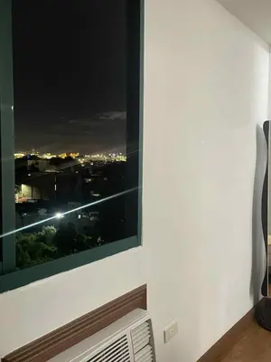 a window with a view of a city at night at Isabelle Garden Hotel & Suites in Manila