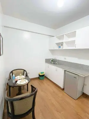 a room with a table and a kitchen with a counter at Isabelle Garden Hotel & Suites in Manila