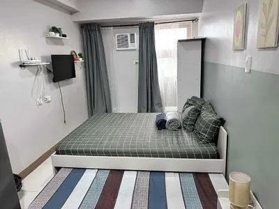 a small bedroom with a bed with a window at Modern Comfort in Pasay with Pool in Manila