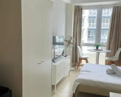 a bedroom with a bed and a tv and a table at City View Condo in Pasig with Pool, WiFi and Netflix in Manila
